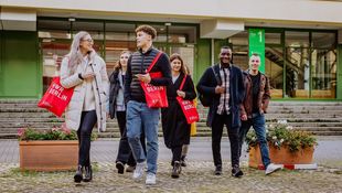 Zwei weibliche und zwei männliche Austauschstudierende lehnen an einem Geländer an der Spree. Im Hintergrund ist die Kuppel des Berliner Doms zu sehen. Foto: © franckreporter/E+/Getty Images
